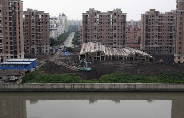 A 13-storey apartment building lies on its side after toppling and burying one worker on Saturday, in Shanghai
